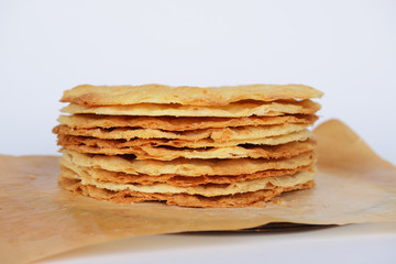 Tasty crispy baked round puff pastry layers of homemade traditional Russian napoleon cake on parchment on white background
