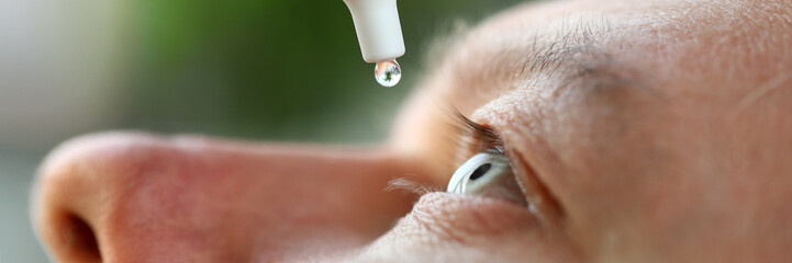 Man putting liquid drops in his eye solving vision problem