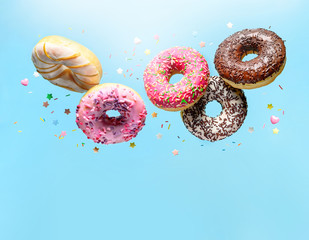 Flying donuts. Mix of multicolored doughnuts with sprinkel on blue background with copy space