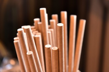 Eco friendly Reusable Straws in the cardboard cup with selective focus and blurred ba. Paper cocktail tubes. Kraft paper straw for drinking coffee or tea. Disposable cocktail tube. 