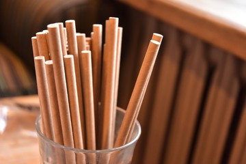 Eco friendly Reusable Straws in the cardboard cup with selective focus and blurred ba. Paper cocktail tubes. Kraft paper straw for drinking coffee or tea. Disposable cocktail tube. 
