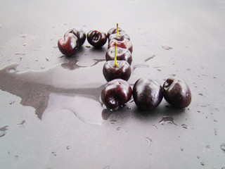The figure 2 formed by cherries. Fresh black cherries on a black gray background