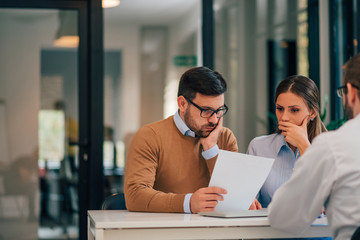 Financial adviser with young couple at banking meeting, portrait.