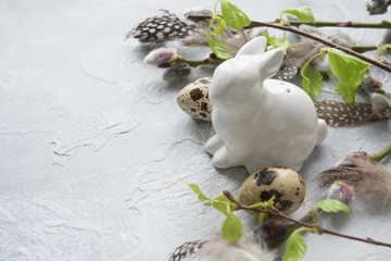 Easter bunny with eggs in grass, spring willow on grey. Space for text. Easter composition.