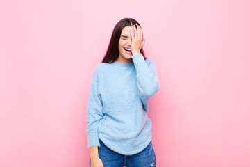 young pretty woman laughing and slapping forehead like saying d‚Äôoh! I forgot or that was a...