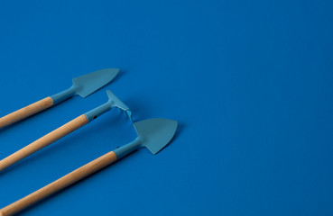 resource of gardening tools shovels and rake on blue classic background