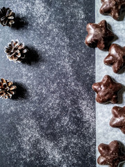 Dark chocolate cookies, gingerbreads and fir-cones on a granite background