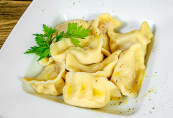 Meat dumplings - russian pelmeni, ravioli with meat on a wooden background