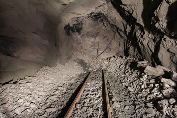 Underground gold mine shaft tunnel drift with rails face wall