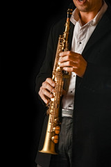 Fototapeta na wymiar soprano saxophone in the hands of a guy on a black background