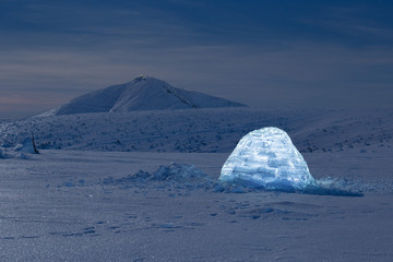 Iluminated igloo during a cold winter nights with bright moonshine