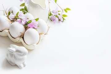 Organic white chicken eggs with spring flowers on white. Easter.