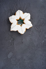 Snowflake shape gingerbread cookie on gray concrete background. Cooking, recipe, card, Christmas concept. Top view, flat lay, copy space, vertical format