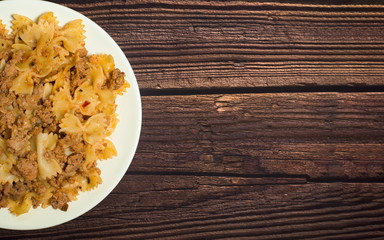 fresh delicious nutritious pasta with meat on a wooden background . half of the plate in the photo. the view from the top. photo for banner, place for text . close up