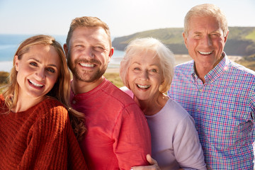 Portrait Of Senior Couple With Adult Offspring On Vacation By The Sea