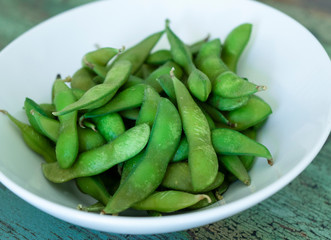 Close shot of steamed fresh edamame bowl on wooden background