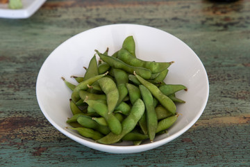 Bowl of Edamame, green beans of boiled soybeans on wooden background. Japanese food.