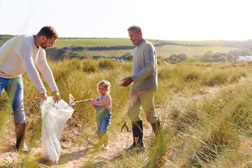 Fototapeta premium Multi-Generation Family Collecting Litter On Winter Beach Clean Up
