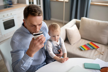 Mature father having morning coffee and holding his daughter