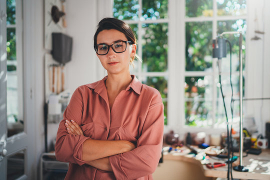Portrait of young female entrepreneur working in her studio, young professional manager wearing casual clothes working in