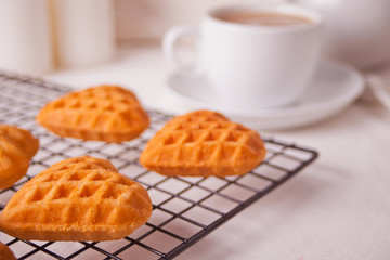 Cup of coffee and a heart shaped cookies on the baking rack
