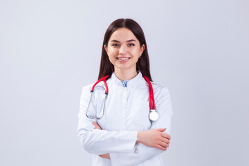 Medical concept of beautiful female doctor in white coat with phonendoscope. Medical student general practitioner. Woman hospital worker looking at camera and smiling, studio, gray background