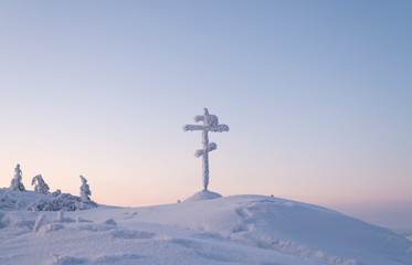 Fototapeta na wymiar Snow-covered Cross on the Olchansky Pass near the village of Ust-Nera, Oymyakon District, Sakha Republic, Russia. The cross is installed near a dangerous Kolyma highway, called the road on bones