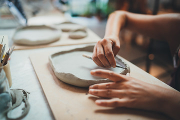 Closeup Image of Female Hands Works with Clay Makes Future Ceramic Plate, Professional Ceramic Artist Makes Classes of Hand Building in Modern Pottery Workshop, Creative People Handcrafted Design - obrazy, fototapety, plakaty