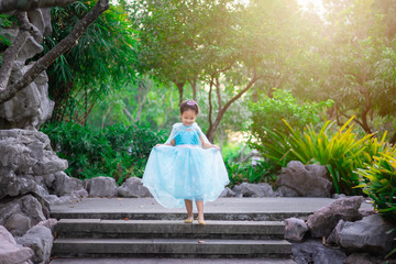 Portrait of cute smiling little girl in princess costume walking down the stairs in the park © domonite