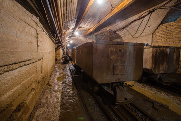 Fototapeta na wymiar Underground gold mine shaft tunnel drift with orecarts wagons