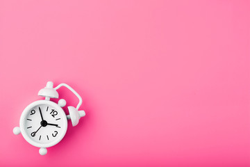 White retro alarm clock on pink background. Concept of time with free space for text.
