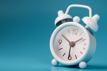 White retro alarm clock on blue background. Concept of time with free space for text.
