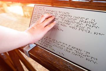 blind woman reads text on a braille sign for the blind
