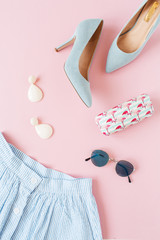 Fashion female clothes and accessories on pink background. Skirt, high-heels, sunglasses, earrings. Flat lay, top view.