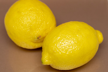 An up close photo of two yellow lemons.