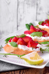 Trout Gravlax on the slice of white bread with ricotta topped with greenery against the white background. Nordic cuisine meal