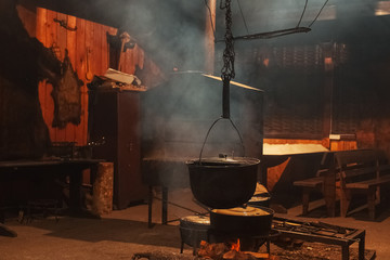 Large cooking pots are prepared using firewood.Metal boilers over a fire in a house with smoke.