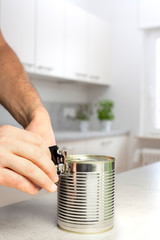 Man opening a can in white kitchen