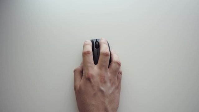 Top Overhead View of Isolated Male Hand Browsing Internet using Wireless Mouse. Scrolls Websites and Clicks while Moving the Mouse on White Table. 