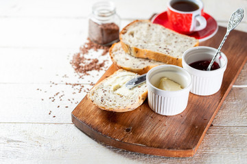 Sliced toast bread with butter on wooden cutting board. Morning breakfast with coffee, butter and toasts.