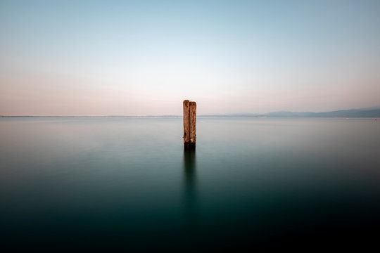Italy, Veneto, Wooden pole in Lake Garda