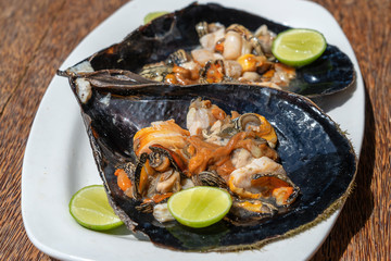 Raw clam meat in a large seashell served for food at a local restaurant on the island of Zanzibar, Tanzania, East Africa