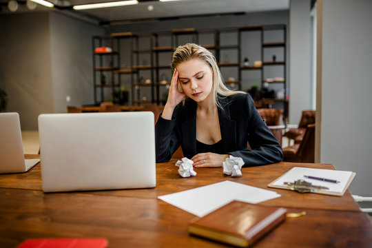 The Girl Manager Sits At The Desk In The Office And Looks With Annoyance At The Crumpled Documents, And Holds Her Hands Over Her Head From Fatigue