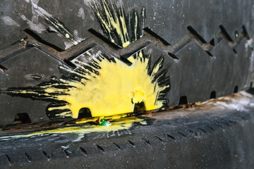 Yellow paint splash from a crashed paintball on an old car tire with a zigzag tread pattern....