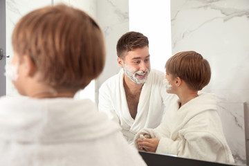 Dad and son with shaving foam on faces in bathroom