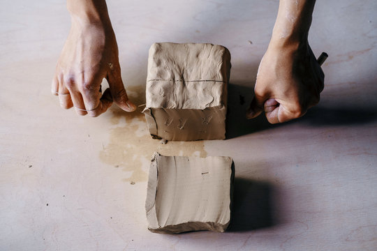 Female potter hands working with clay in workshop. White desk on background