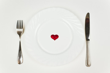 Red heart on plate on white background. Healthy diet concept. A romantic dinner for two on Valentine's Day, February 14th.