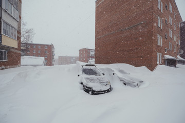 Heavy snowfall. cars under snow parked near houses in winter city