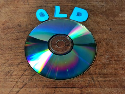 Compact disk on wooden board and the word old. obsolete technology concept