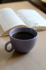 Cup of tea, book and gypsophila flowers on wooden table. Selective focus.